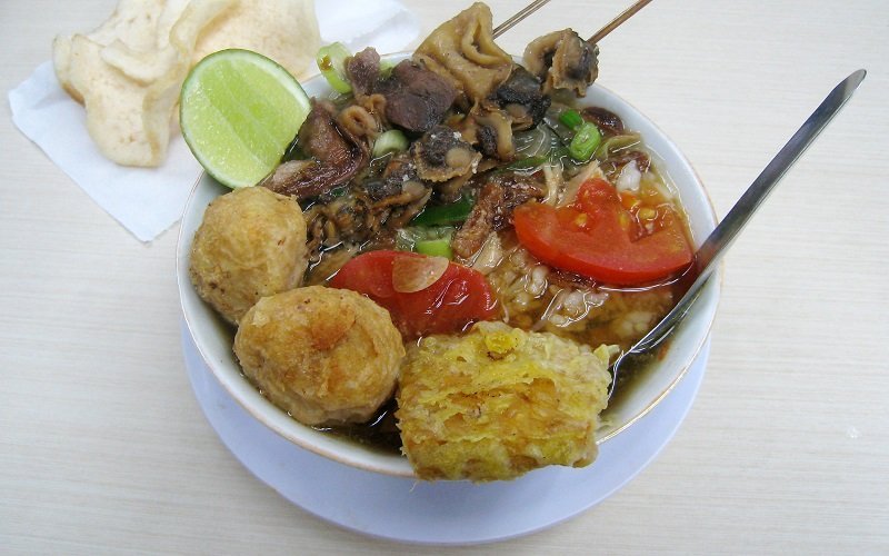 Soto Bangkong, a variant of Soto from Semarang, Central Java. The chicken soto with rice vermicelli and tomato, served with potato perkedel, fried tempe, and satay of cockles and tripes, with lime and krupuk.